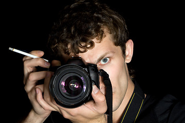 Image showing The young man - photographer behind work. Isolated on a black ba