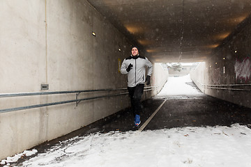 Image showing happy man running along subway tunnel in winter