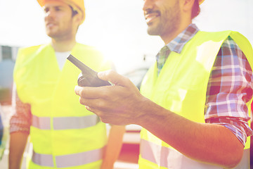 Image showing close up of builders in vests with walkie talkie