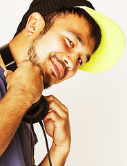 Image showing young asian man in hat and headphones listening music on white b