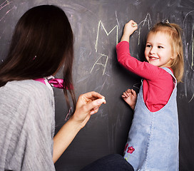 Image showing little cute blond girl writing on blackboard in classroom with teacher, lifestyle education people concept