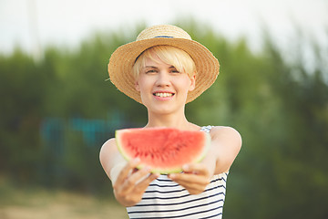 Image showing Beautiful girl in straw hat eating fresh watermelon. Film camera style