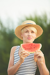 Image showing Beautiful girl in straw hat eating fresh watermelon. Film camera style