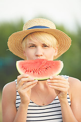 Image showing Beautiful girl in straw hat eating fresh watermelon. Film camera style