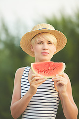 Image showing Beautiful girl in straw hat eating fresh watermelon. Film camera style