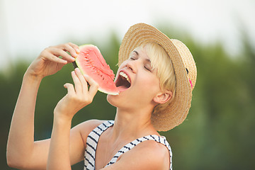 Image showing Beautiful girl in straw hat eating fresh watermelon. Film camera style