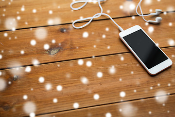 Image showing close up of blank smartphone and earphones on wood