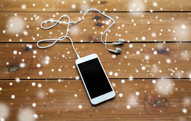 Image showing close up of blank smartphone and earphones on wood