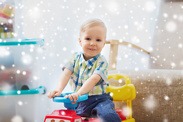 Image showing happy little baby boy driving ride-on car at home