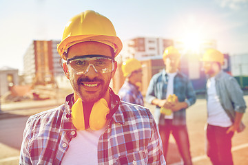 Image showing smiling builder with hardhat and headphones