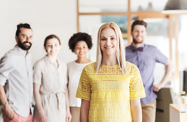 Image showing happy young woman over creative team in office