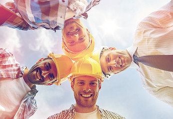 Image showing close up of builders wearing  hardhats in circle