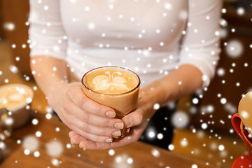 Image showing close up of hands with latte art in coffee cup