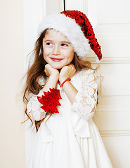 Image showing little cute girl in santas red hat waiting for Christmas gifts. 