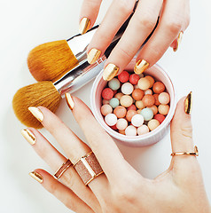 Image showing woman hands with golden manicure and many rings holding brushes,