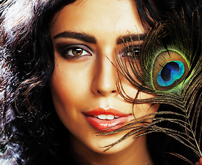 Image showing young sensitive brunette woman with peacock feather eyes close up