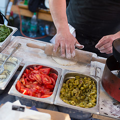 Image showing Chef making pita bread for falafel roll outdoor on street stall.