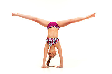 Image showing The teenager girl doing gymnastics exercises isolated on white background