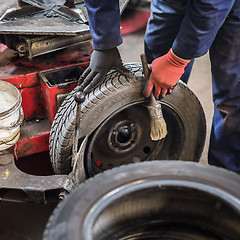 Image showing Professional auto mechanic replacing tire on wheel in car repair service.