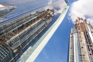 Image showing Skyscrappers construction site with cranes on top of buildings.