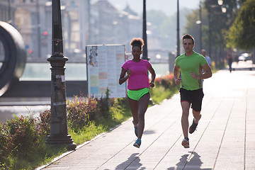 Image showing young smiling multiethnic couple jogging in the city