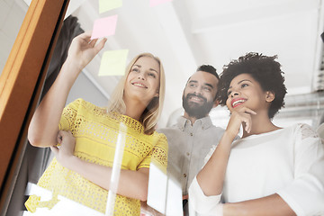 Image showing happy creative team writing on stickers at office