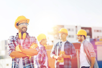 Image showing group of smiling builders in hardhats outdoors