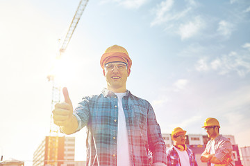 Image showing group of smiling builders in hardhats outdoors