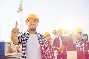 Image showing group of smiling builders in hardhats outdoors