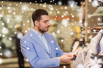 Image showing happy young man choosing clothes in clothing store