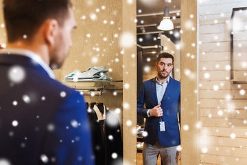 Image showing man trying jacket on at mirror in clothing store