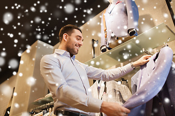 Image showing happy young man choosing clothes in clothing store