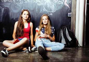 Image showing back to school after summer vacations, two teen real girls in classroom with blackboard painted together