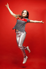 Image showing young pretty emitonal posing teenage girl on bright red background jumping with flying hair, happy smiling lifestyle people concept