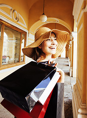 Image showing young pretty smiling woman in hat with bags on shopping at store