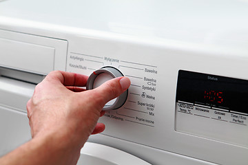 Image showing man hand switches on washing machine