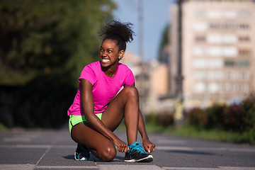 Image showing African american woman runner tightening shoe lace