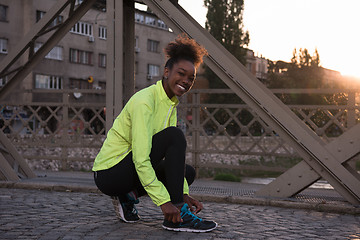 Image showing African american woman runner tightening shoe lace