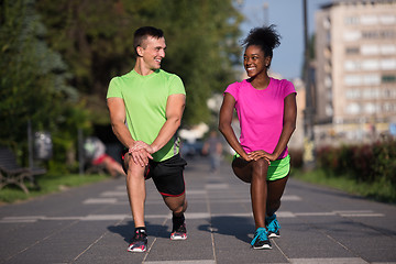 Image showing jogging couple warming up and stretching in the city