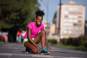 Image showing African american woman runner tightening shoe lace