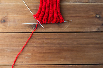 Image showing hand-knitted item with knitting needles on wood