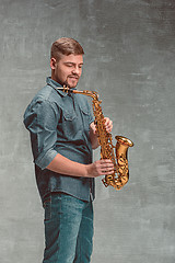 Image showing Happy saxophonist with sax over gray background