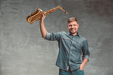 Image showing Happy saxophonist with sax over gray background