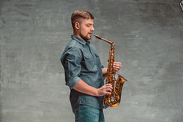 Image showing Happy saxophonist with sax over gray background