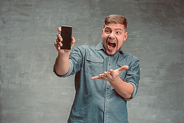 Image showing The young smiling caucasian businessman on gray background with phone