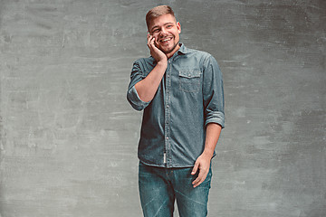 Image showing The young smiling caucasian businessman on gray background talking with phone