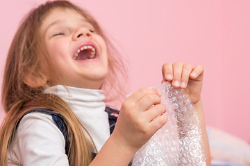 Image showing The girl laughs infectiously, playfield balls on the packaging bag