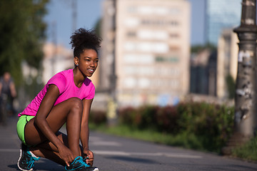 Image showing African american woman runner tightening shoe lace