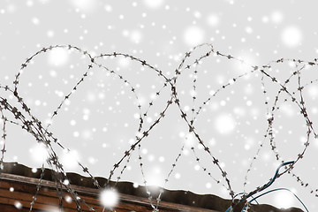 Image showing barb wire fence over gray sky and snow