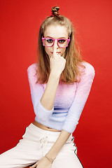 Image showing young pretty emitonal posing teenage girl on bright red background, happy smiling lifestyle people concept